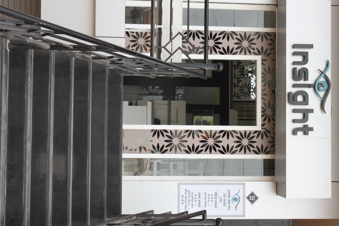 Stair landing at Insight Institute aligned with the brand marquee, with floral lattice screens flanking the glazed entry door